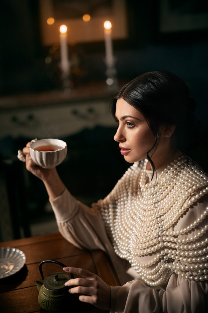 Woman drinking tea by candlelight, cinematic fashion retouch, moody tones