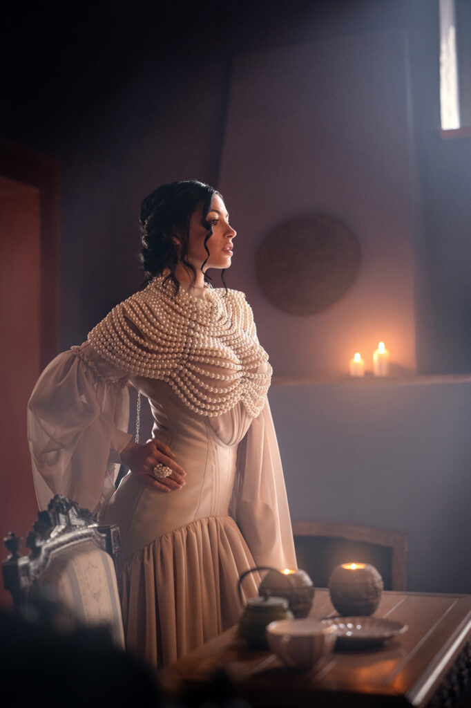 Model standing in dramatic light with pearls, high-end editorial retouching